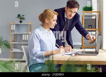 Two company employees working together, looking through accounting data on spreadsheets on laptop. Stock Photo