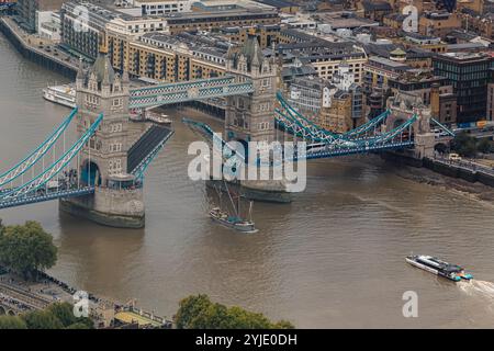 A tall mast boat passes under the raised Tower Bridge,completed in 1894 it is one of London 's most recognisable landmarks ,City Of London,UK Stock Photo