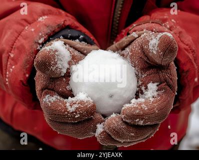 Gloved Hands Holding a Snowball in Winter Stock Photo