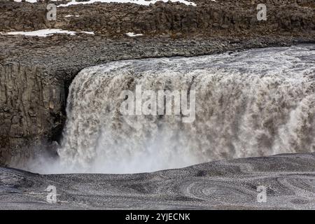 Dettifoss waterfall in Vatnajokull National Park in Northeast Iceland, waterfall view with basalt columns, ice and snow and water spray. Stock Photo