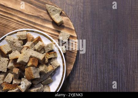 On the table is a plate with cubes of black bread crackers. Stock Photo