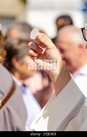 a catholic priest holding a host during the sacrament of communion at an outdoor service Stock Photo