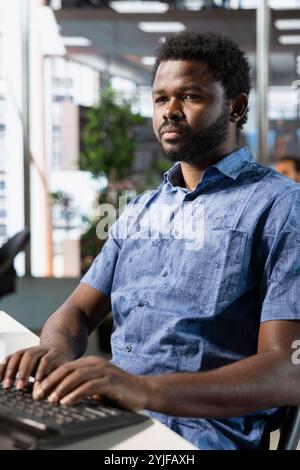 Tech savvy IT staff member doing software quality assurance, writing source code on computer. IT professional at work in office inspecting coding on PC, looking to fix potential bugs and glitches Stock Photo