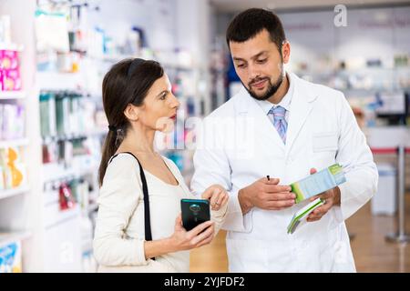 Male pharmacist consulting woman customer in drugstore Stock Photo