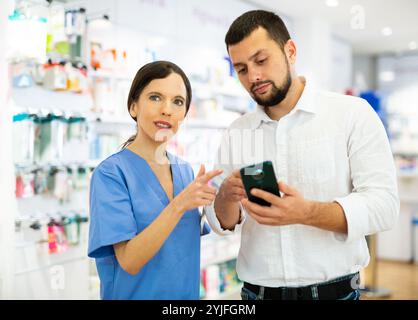 Female pharmacist consulting male customer in drugstore Stock Photo