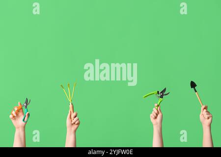 Female hands with gardening tools on green background Stock Photo
