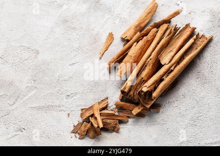 A pile of broken cinnamon sticks and pieces arranged on a white textured background. Stock Photo