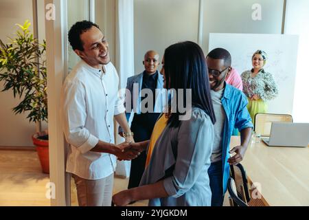 A diverse business team meets with a client in a modern office environment. They exchange smiles and handshakes, signifying a successful meeting and a Stock Photo