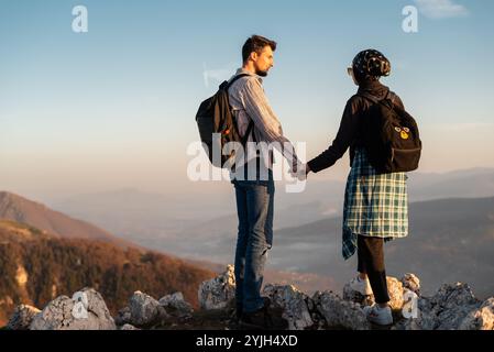 A happy couple who hikers enjoys a break look at the top of the mountain adventure travel. Stock Photo