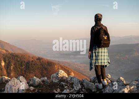 A woman traveler enjoys a break look at the top of the rocky mountain during the hike, adventure travel. Stock Photo
