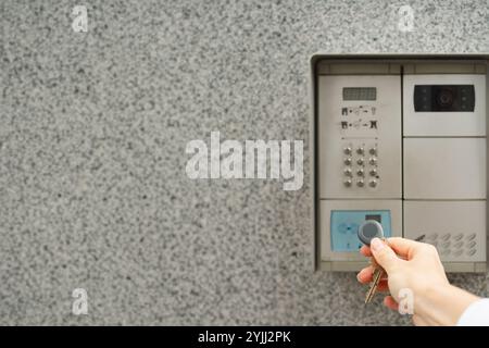 Woman's hand with key fob against intercom Stock Photo