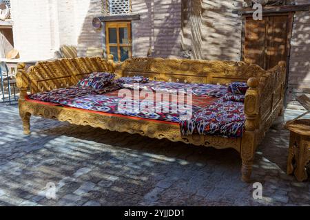 A long wooden bed with a colorful blanket and pillows Stock Photo