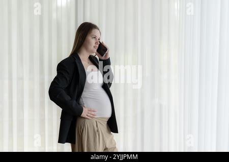 White pregnant woman talking on the phone. Pregnant businesswoman talking on the phone while working. Stock Photo