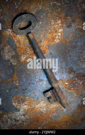 rusting old door key on rusting metal surface Stock Photo