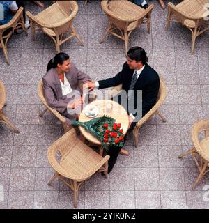 Lifestyle. Overhead viewpoint of young executive romantic couple sitting at table in café. Stock Photo