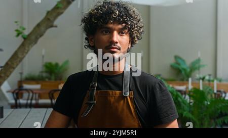 Happy joyful Latino American ethnic man male smiling cafe worker in apron guy waiter cleaner barista portrait small business owner employee looking at Stock Photo