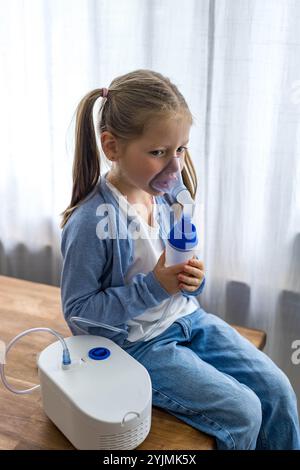 A 5-year-old girl at home uses a nebulizer, taking deep breaths to aid her respiratory health. High quality photo Stock Photo