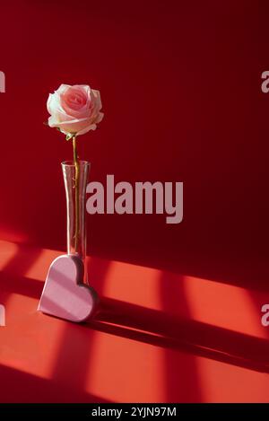 Pink rose in a vase with a pink heart at the base. Stock Photo
