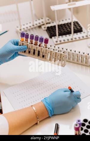 Technician analyzing blood samples in a lab with detailed documentation for medical research Stock Photo