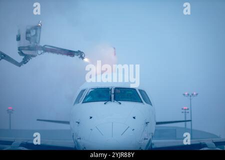 Deicing of airplane before flight. Winter frosty night and ground service at airport during snowfall. Stock Photo