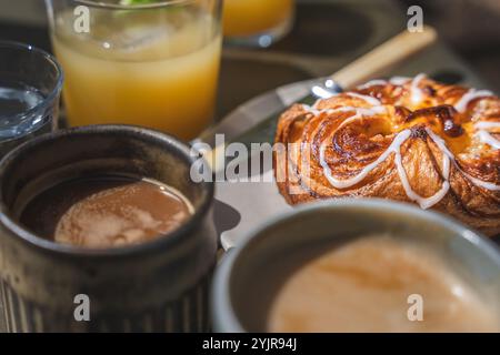Close up food image of a freshly baked Danish Pastry with flaky pastry, orange juice and hot coffee at an outdoor cafe table Stock Photo