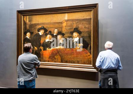 Visitors looking at The Wardens of the Amsterdam Drapers Guild, known as 'The Syndics', by Rembrandt van Rijn in the Rijksmuseum, Amsterdam. Stock Photo