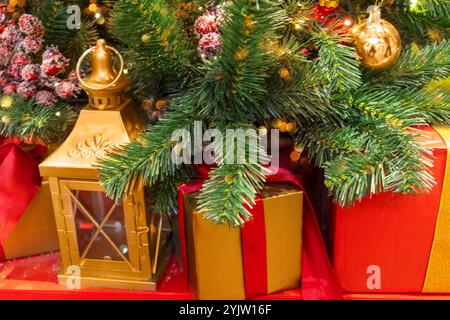 Golden lantern and presents under Christmas tree decorated with ball and red berries. Stock Photo