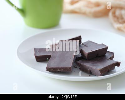 A plate of homemade dark chocolate on a table near a mug of coffee. Stock Photo