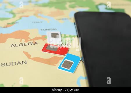 SIM cards and smartphone on world map, closeup Stock Photo