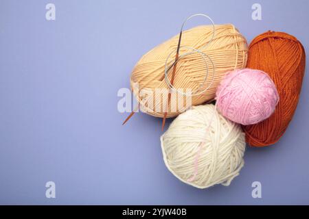 Different yarns, knitting needles on purple background. Autumn. Stock Photo