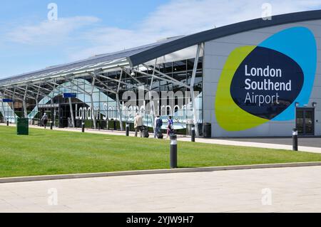 London Southend Airport. Passengers with luggage heading towards the terminal building, with London Southend Airport logo, symbol Stock Photo