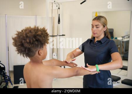 Experienced physical therapist works with ayoung patient in rehabilitation center Stock Photo