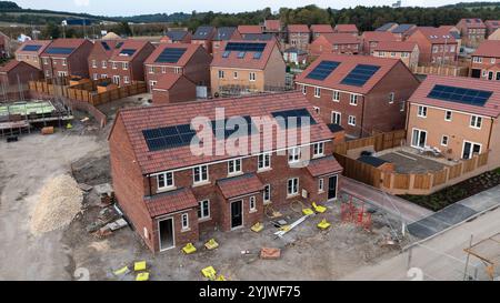 The roof of a row of new build houses on a construction site under construction with roof integrated or In-Roof solar panels for cheap and sustainable Stock Photo