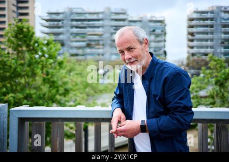 Portrait of handsome Caucasian mature man posing leaning on rail in front of garden at nursing home. Stock Photo