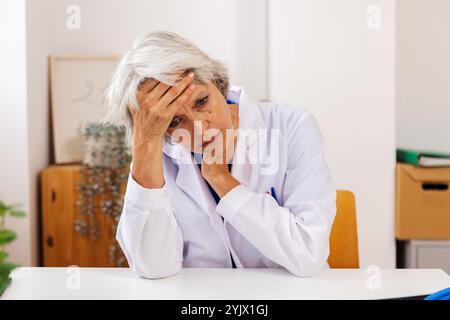 Senior female doctor experiencing burnout and stress at work Stock Photo