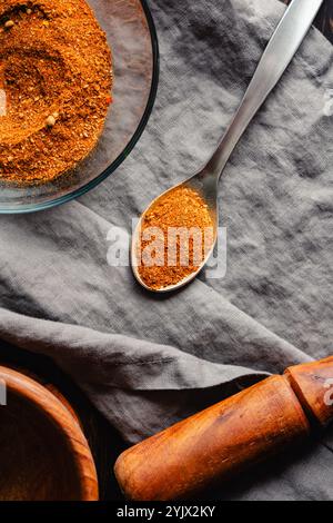 Spoonful of Homemade Berbere Spice Blend Close-up: Mixture of ground herbs and spices in a metal spoon with a glass bowl and wooden mortar and pestle Stock Photo