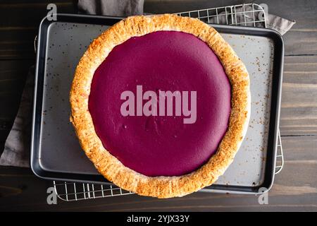 Purple Sweet Potato Pie with Pecan Shortbread Cookie Crust: Directly above a homemade sweet potato pie on a sheet pan and wire cooling rack Stock Photo