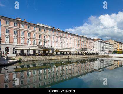 Trieste, Italy - June 26, 2024: NE facade along the Canal Grande between Via Roma Bridge and the Piazza Sant'Antonio Nuovo, which is also reflected in Stock Photo