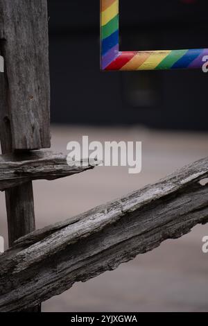 Part of wooden fence and one corner of a square colorful frame with  rainbow stripes hand painted empty framed space background or backdrop type space Stock Photo