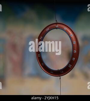 Hand painted red with white and blue  flowers round circular empty wooden frame hanging by a wire with blurred pastel colored background or backdrop Stock Photo