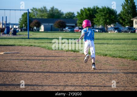 Youth girl softball player running to first base after batting Stock Photo