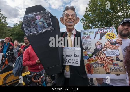 London, UK. 9th September 2017. A man wearing a Tony Blair mask holds a small coffin and a poster about the army at the East gate of the worlds's largest arms fair, DSEI, the Defence & Security Equipment International, backed by the UK government where arms companies and arms dealers sell weapons to countries around the world including many repressive regimes.   He was one of several hundred protesters who blocked the road to hold up lorries entering the site. Police tried to clear the road and made several arrests including two who had formed a lock-in and another who lay under the wheels of Stock Photo