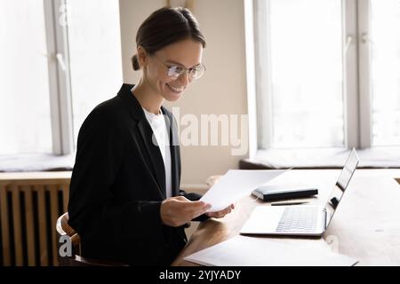 Smiling businesswoman reading message on cellphone at workplace Stock Photo