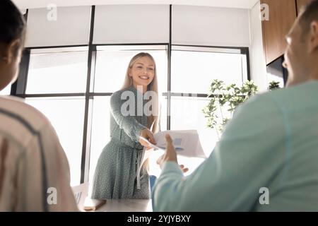 Happy successful young professional woman giving paper marketing reports Stock Photo