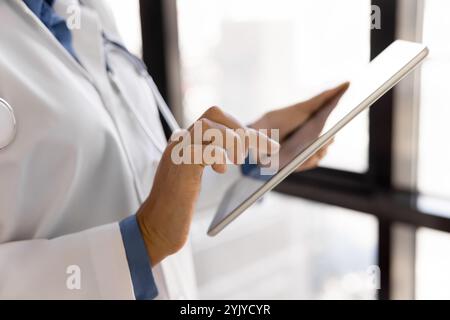 Closeup female therapist in white lab coat using modern tablet Stock Photo