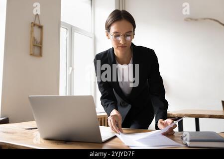 Woman reviewing papers, reading documents working in office Stock Photo