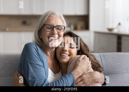 Happy older woman in glasses cuddling tightly her adult daughter Stock Photo