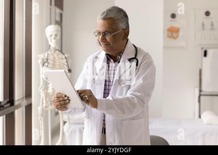 Mature therapist using modern digital tablet at workplace Stock Photo