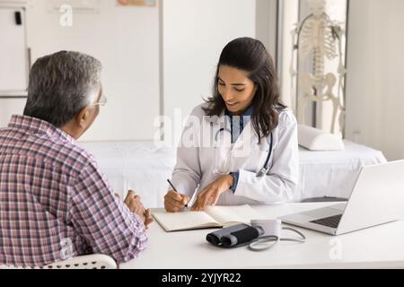 Doctor writing in casebook journal male patient health complaints Stock Photo