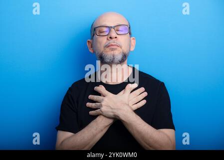 Bearded, bald man wearing prescription glasses and a black shirt with his arms crossed on his chest. Confident and focused. Studio shot. Stock Photo